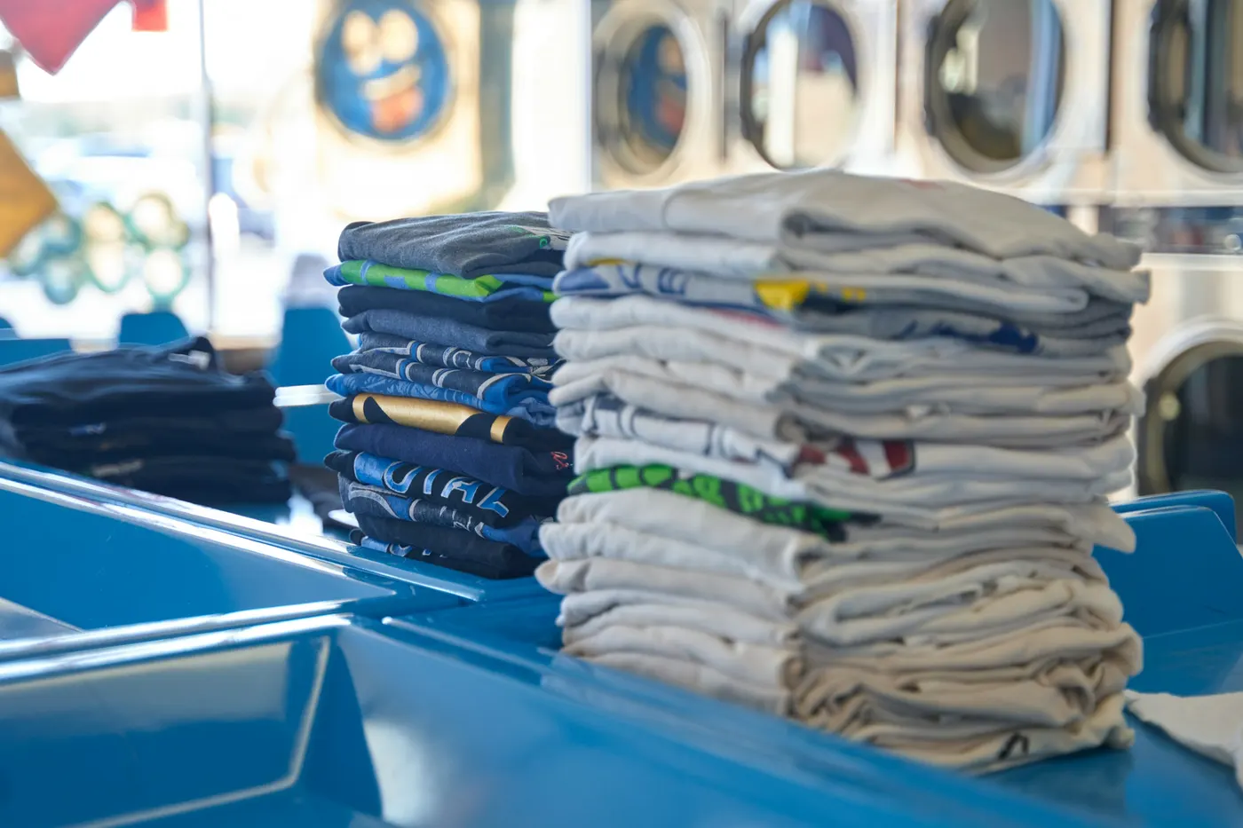 Stacks of freshly laundered, folded shirts on a blue counter